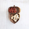 Wooden acorn-shaped bowl with red and white vase filler on a light background