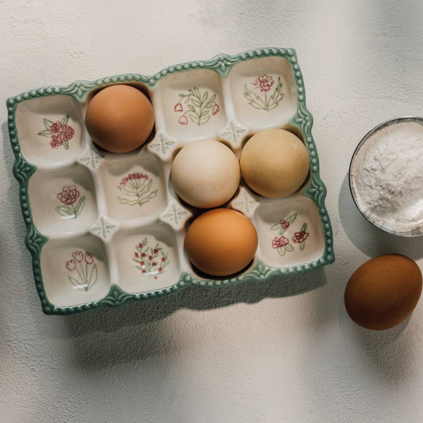 Decorative egg holder with eggs on a light surface next to a glass of milk.