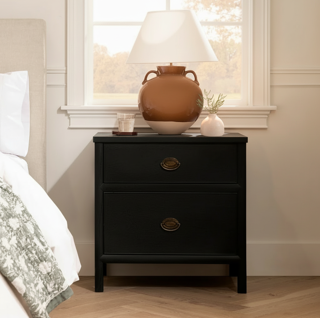 Black nightstand with decorative items next to a bed in a bedroom.