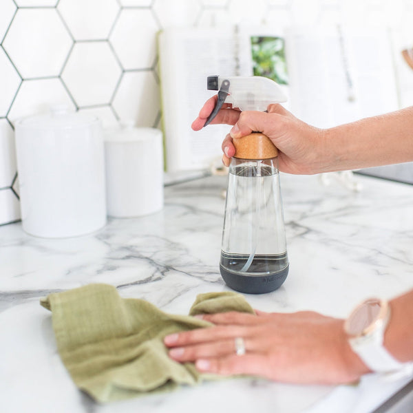 person holding glass spray bottle in kitchen