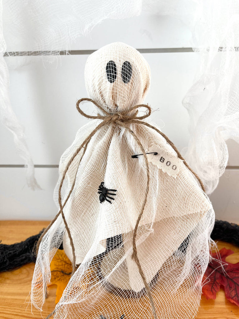 Two handmade fabric ghost statues in different sizes with a wooden circle base, intended for Halloween decorating.