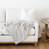 White sofa with a beige blanket and pillows in a minimalistic living room.