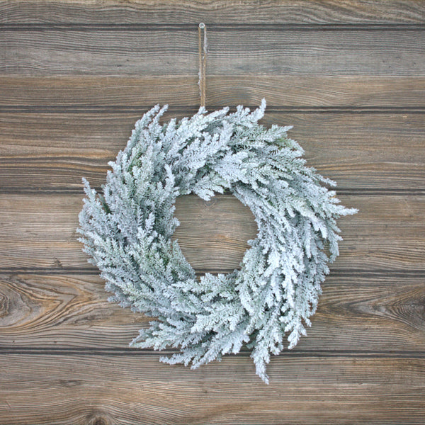 A frosted cedar berry wreath placed on a wooden surface.