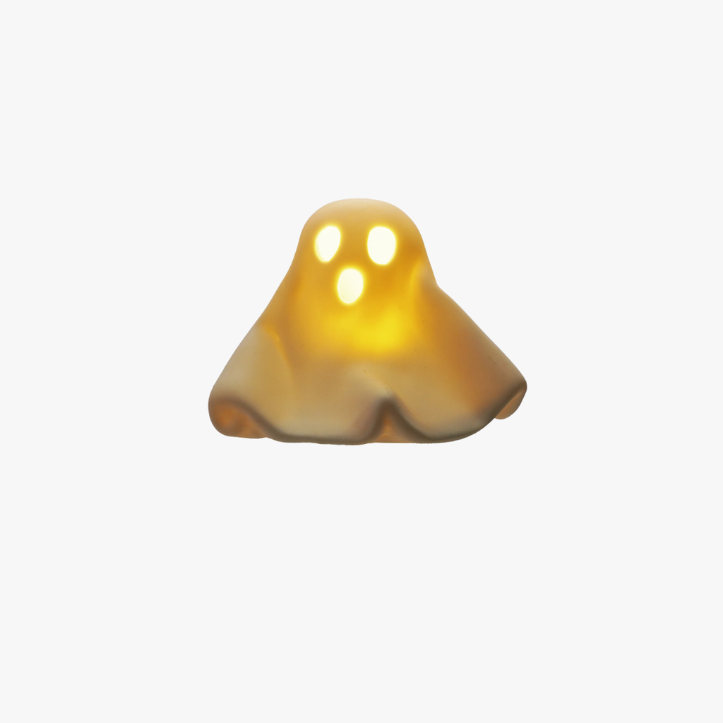 A small ghost-shaped decorative light or figurine in glowing warm yellow and amber tones, centered on a plain light gray background.