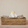 White ghost figurine on a stack of brown paper with a beige background