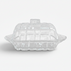 Clear glass butter dish with a lid on a white background
