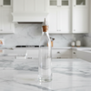 Clear glass bottle with stainless steel spout displayed in kitchen