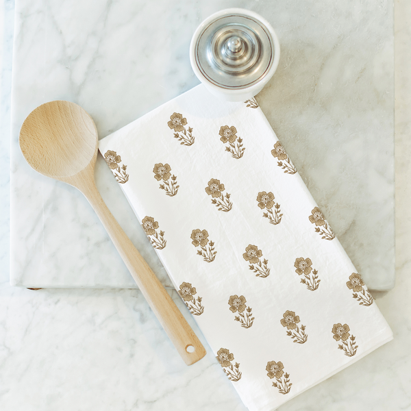 Floral-patterned towel with wooden spoon and white container on marble surface.  organic modern decor