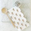 Floral-patterned towel with wooden spoon and white container on marble surface