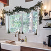 Kitchen with wooden cabinets, white sink, Christmas garland, and Christmas decorations.