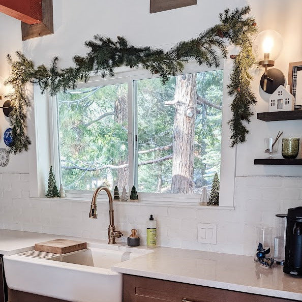 Kitchen with wooden cabinets, white sink, Christmas garland, and Christmas decorations.