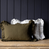 Green pillow with ruffled edges on a wooden surface against a dark paneled wall