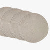 Set of four round woven placemats on a white background