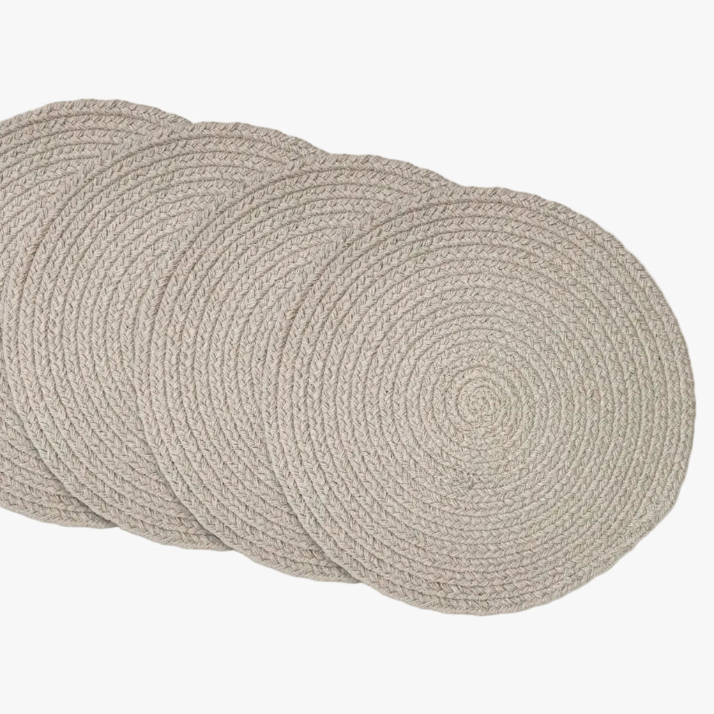 Set of four round woven placemats on a white background