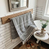 Bathroom with wooden towel rack, gray plaid towel, and small round table with items.