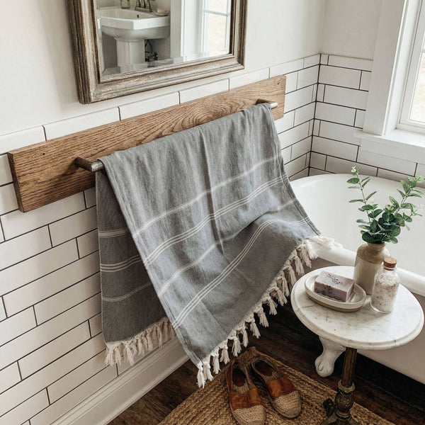 Bathroom with wooden towel rack, gray plaid towel, and small round table with items.
