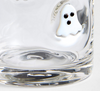 A close-up of a clear glass tumbler with a small white ghost decoration featuring black eyes on the side.