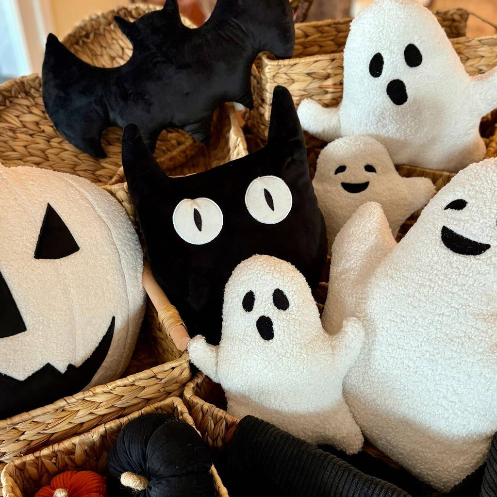 Halloween-themed plush pillows including cats, ghosts, and pumpkins in a woven basket.