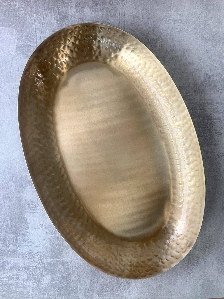 Hammered brass oval tray on a gray surface