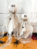 Handmade cotton and cloth ghost statues in varying sizes, displayed with spider decorations, used for Halloween decorating.