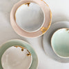 Three ceramic ring dishes with gold accents on a light background