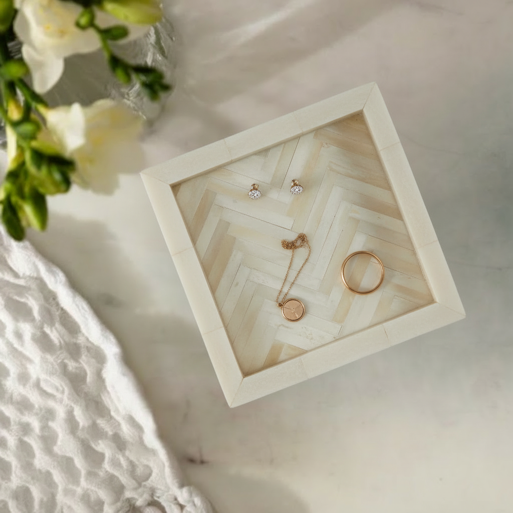 Square neutral tray with herringbone pattern on a marble surface with flowers in the background