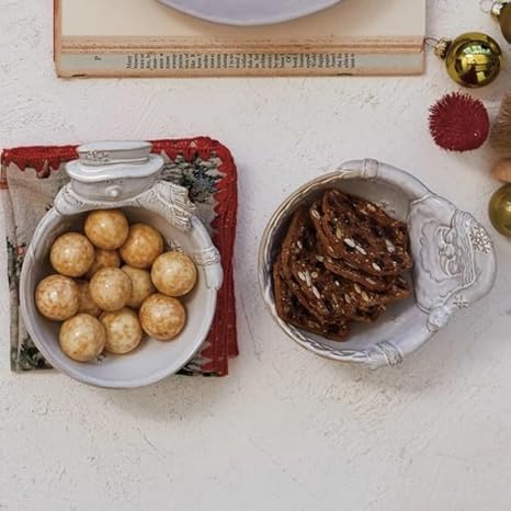 Two decorative bowls filled with gold balls and pretzels on a textured surface.