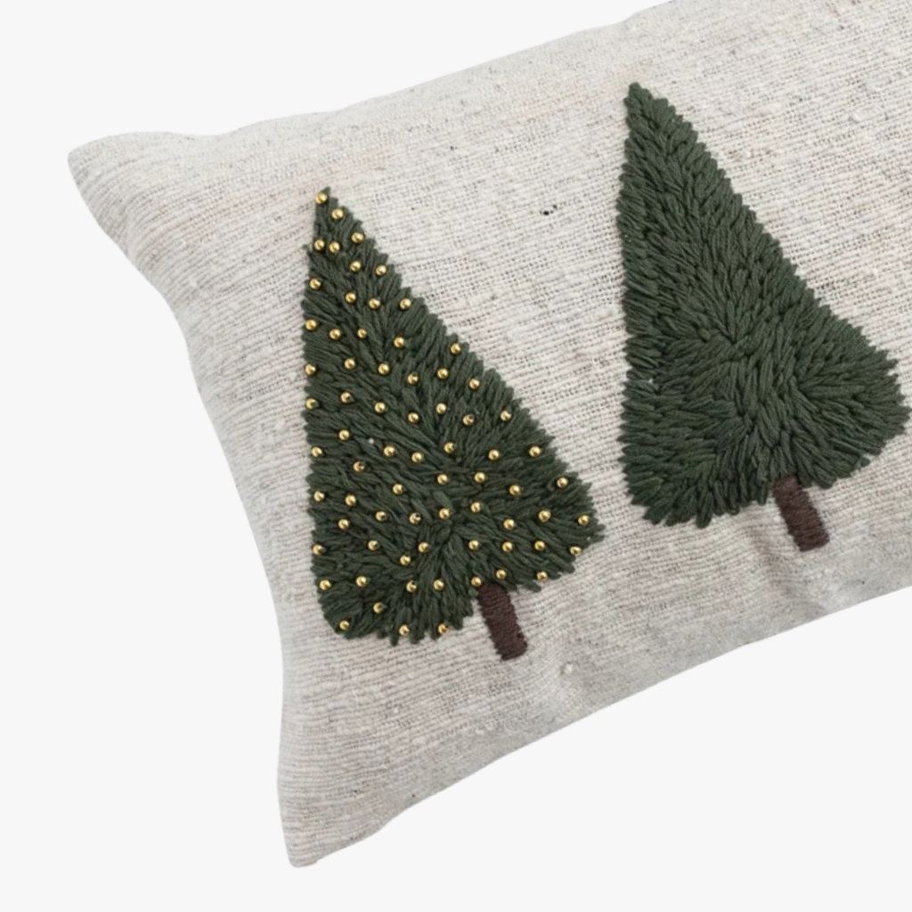 Decorative christmas throw pillow with embroidered green trees on a beige background