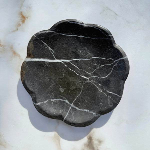 Black marble leaf-shaped dish on a marble surface
