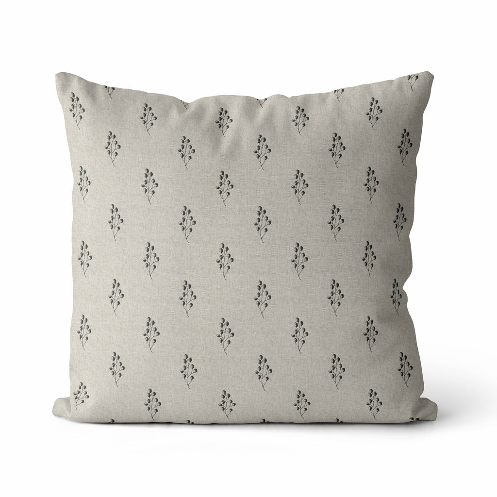 A square throw pillow in a light beige linen fabric with a repeating black floral pattern, shown against a plain white background.