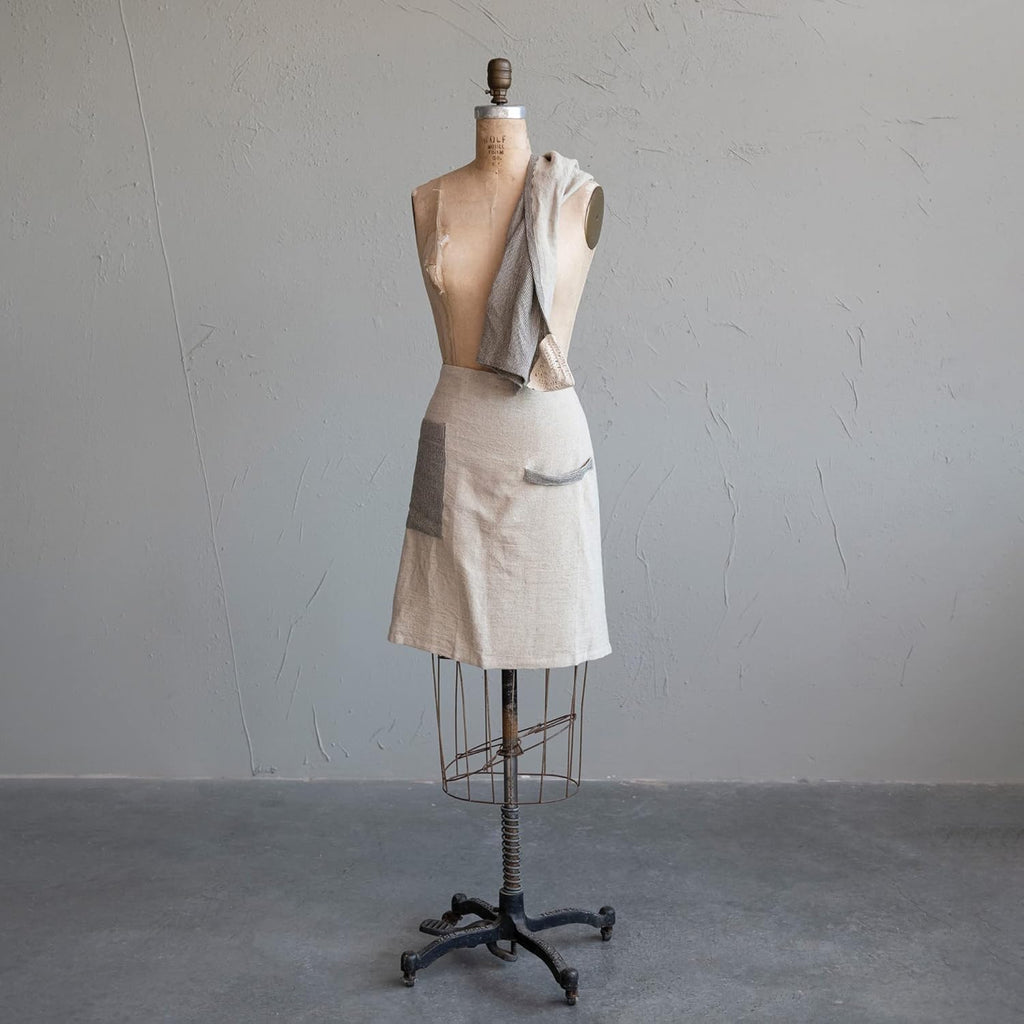 Mannequin wearing a linen and black half apron on a gray background
