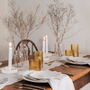 Elegant table setting with table runner, candles, gold and white decor on a wooden table. organic modern home decor