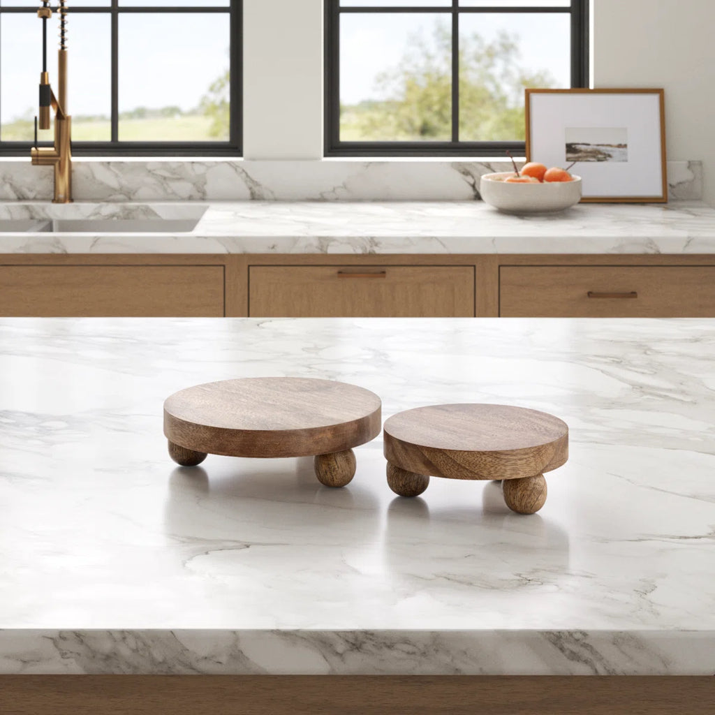Two wooden risers on a marble countertop in a kitchen.