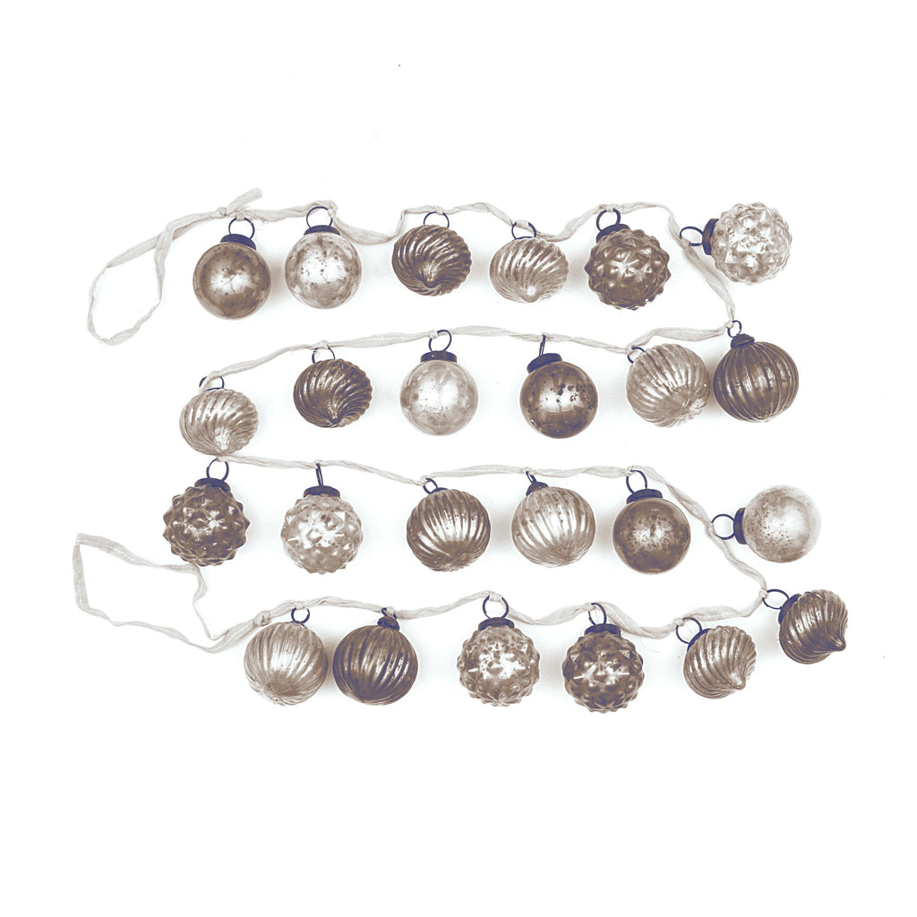 String of decorative christmas garland with mercury glass bulb ornaments on a white background.