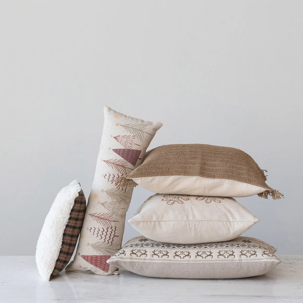 Collection of decorative christmas throw pillows with various patterns on a light surface.