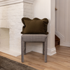 Checkered stool with a green pillow against a white brick fireplace.