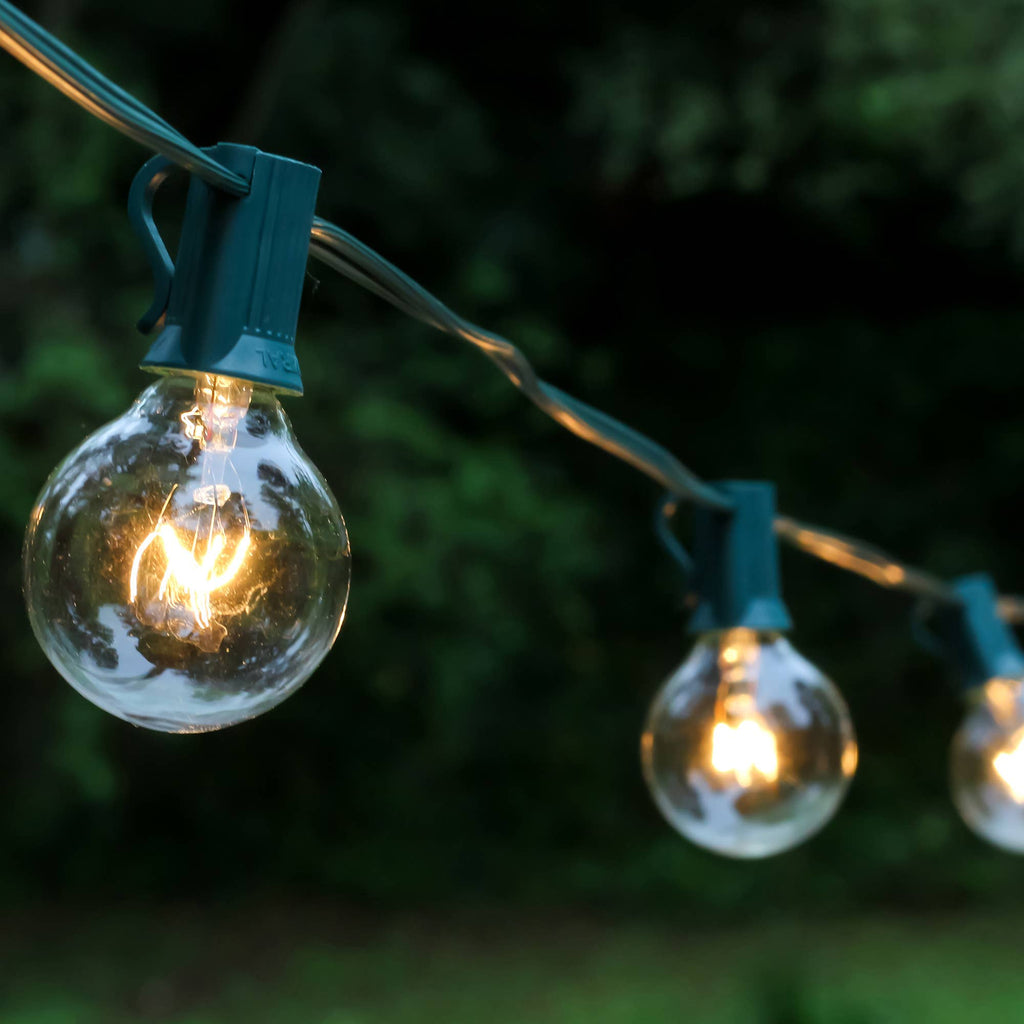 String of outdoor lights with clear bulbs and green clips against a dark background
