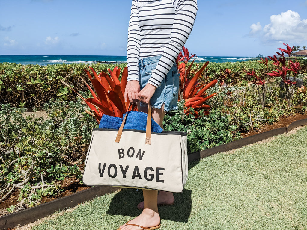 girl on vacation holding bon voyage bag