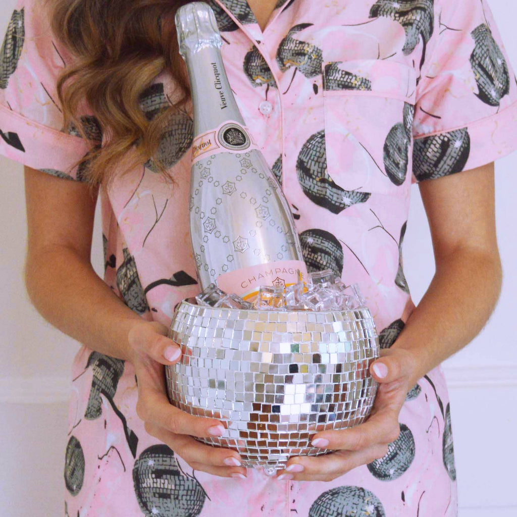 Person holding a bottle of champagne in a disco ball ice bucket