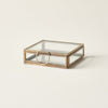 Glass box with brass frame on a light beige background