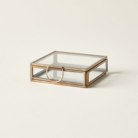 Glass box with brass frame on a light beige background
