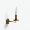 Brass wall-mounted candle holder with a white candle on a white background