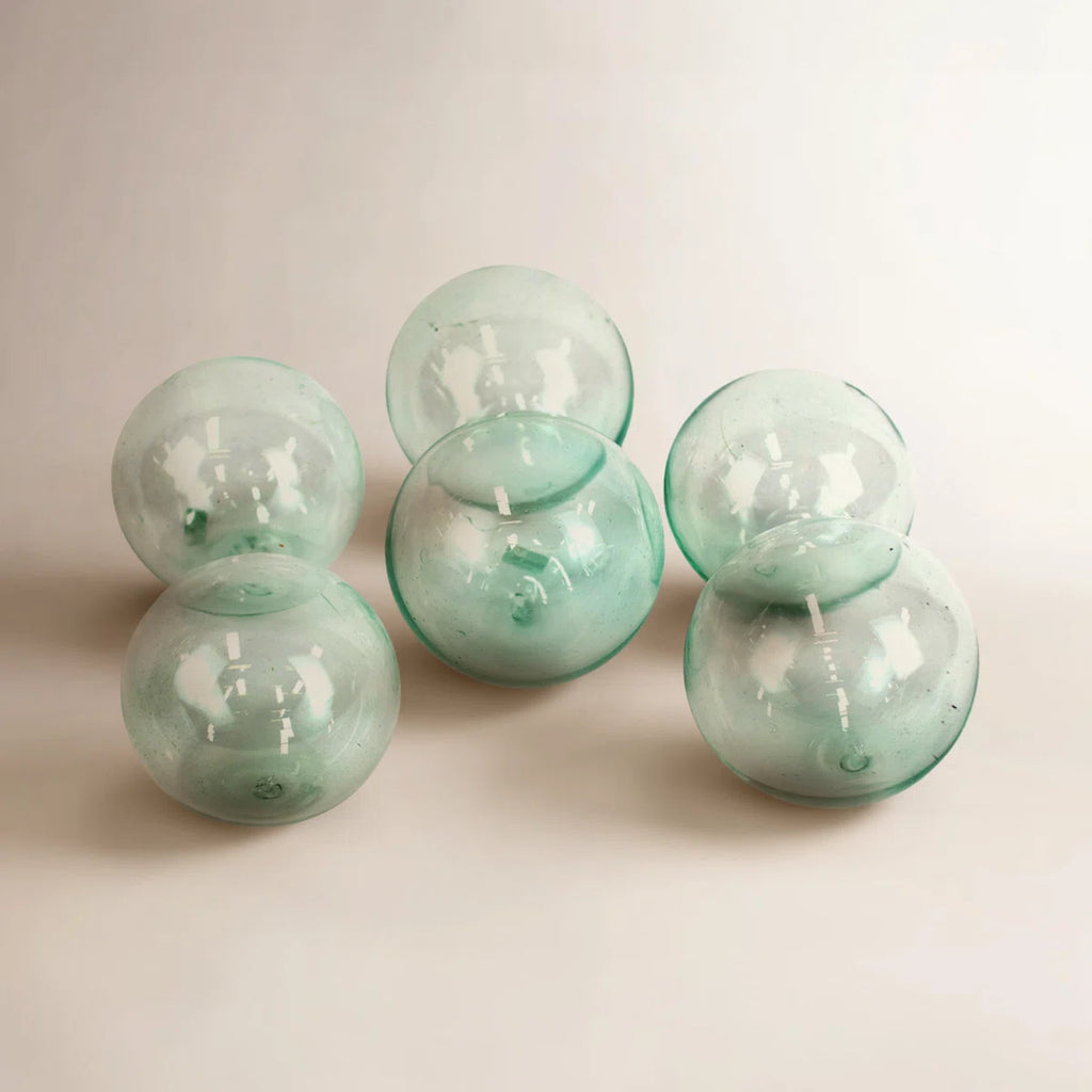Set of six green glass spheres on a light beige background