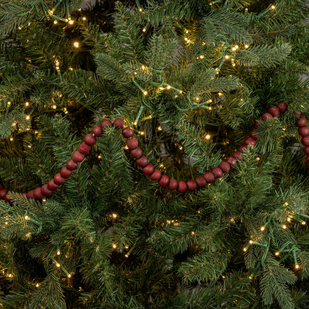 Red bead garland on a decorated Christmas tree with lights