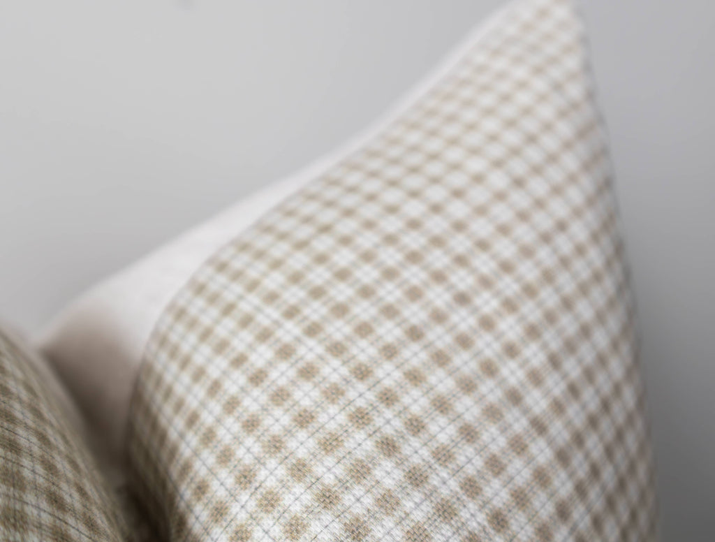 Close-up of a textured pillow with a plaid pattern on a neutral background