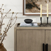 Wooden sideboard with decorative items including candles and books, with a framed abstract painting in the background.