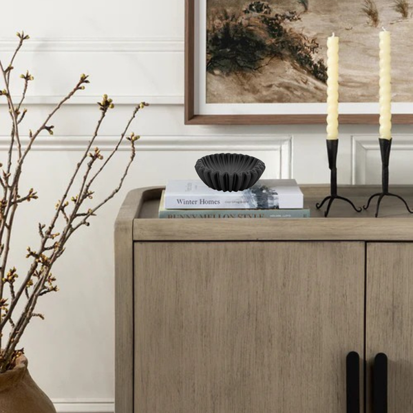 Wooden sideboard with decorative items including candles and books, with a framed abstract painting in the background.