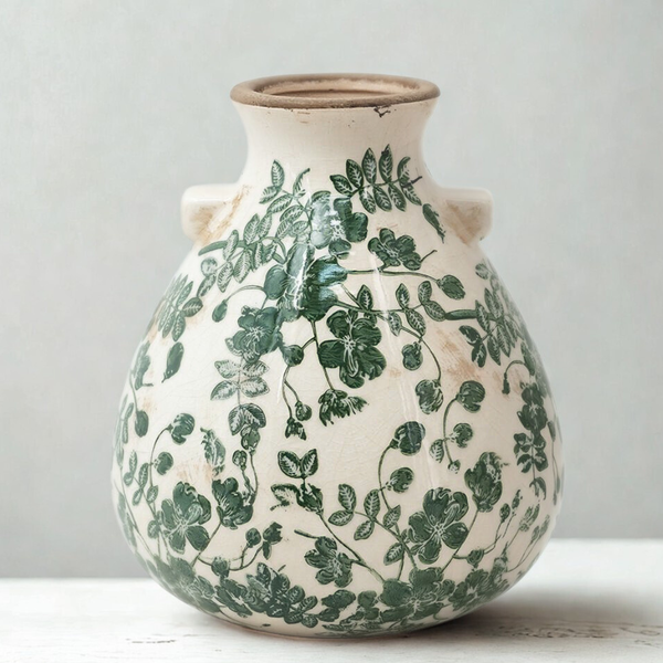 Ceramic vase with green leaf patterns on a light background