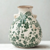 Ceramic vase with green leaf patterns on a light background