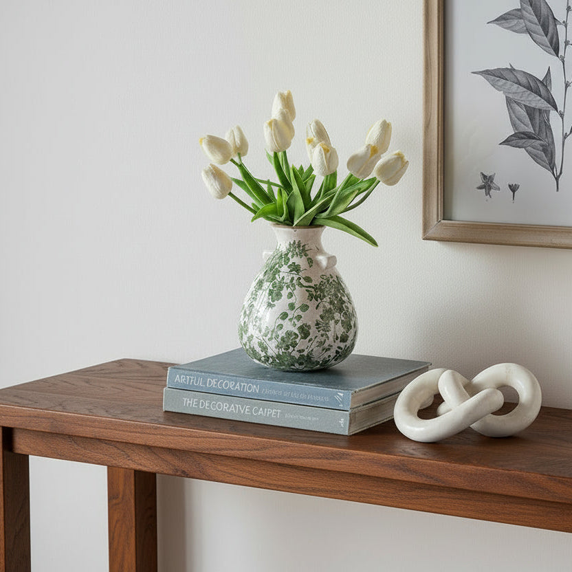 Wooden console table with decorative items including a vase with tulips, books, a knot sculpture, and a candle.